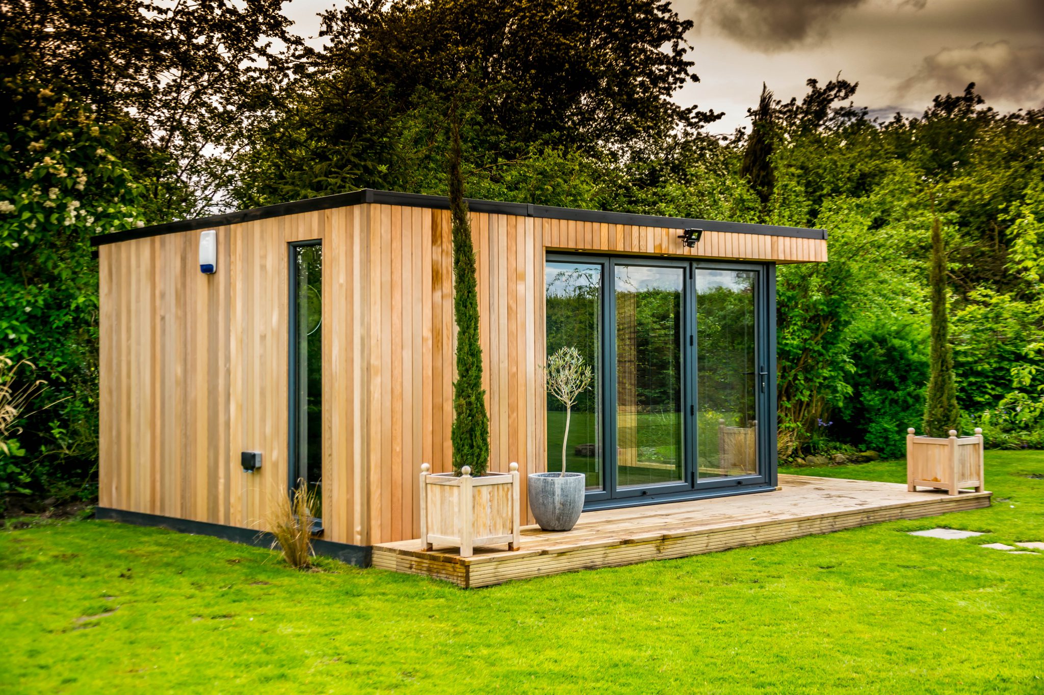 Luxury garden building with bi-fold doors, cedar cladding and deck