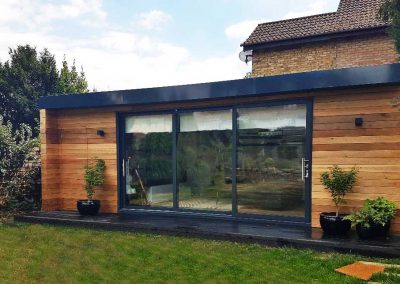 Exterior of garden room with horizontal cedar cladding and large sliding doors